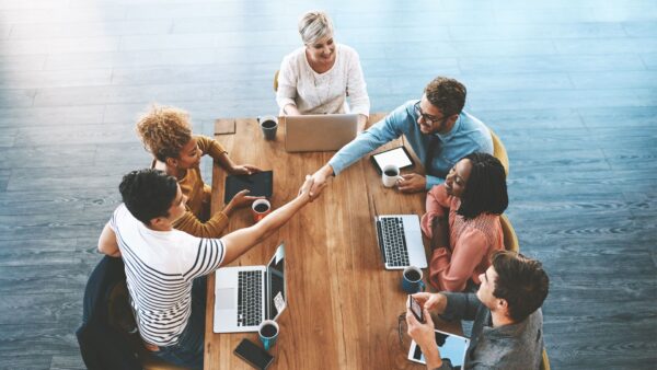 Team meeting with two individuals shaking hands