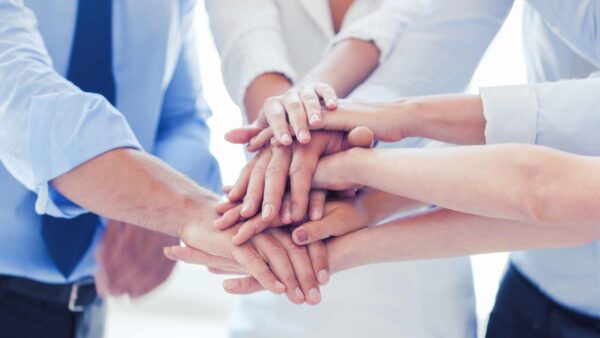 Group of people placing their hands together in a show of unity and teamwork