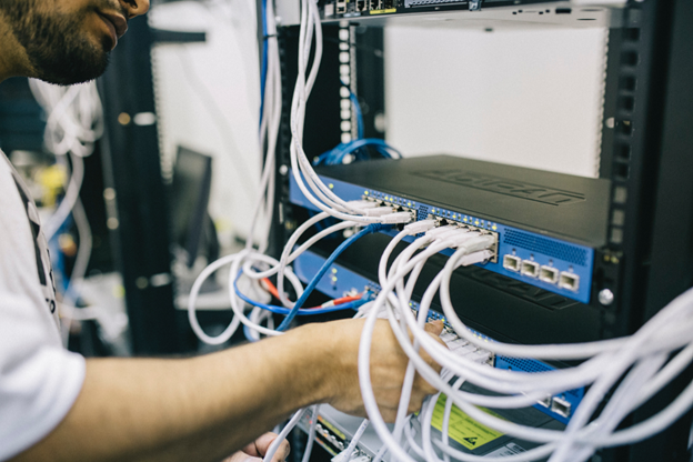 A male worker works with network cables in a server room.